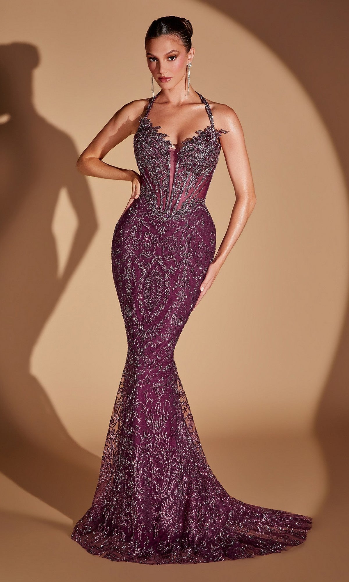 A woman wearing the Ladivine CD695 Sequin-Embroidery Halter Prom Gown in plum, featuring an elegant fitted mermaid silhouette and sparkling silver beading, poses against a beige background.