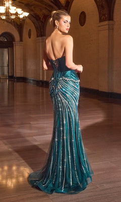 A woman wearing the Strapless Long Beaded Prom Dress: Ladivine CD697 with a lace-up back stands in an ornate hallway, looking over her shoulder.