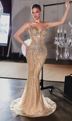 A woman in the gold Strapless Beaded Prom Dress: Ladivine CD715, featuring intricate beadwork and sequins, stands indoors near a chandelier and studio lighting equipment.