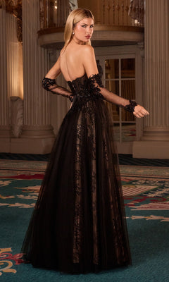 A woman in the Ladivine CD717 Strapless Black Beaded Prom Gown with sheer sleeves stands on a patterned carpet in an ornate, columned room.