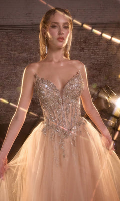 A woman in the Lace-Up Strapless Prom Ball Gown: Ladivine CD721, featuring a glitter tulle skirt and beaded corset, stands in a softly lit room with a brick wall background.