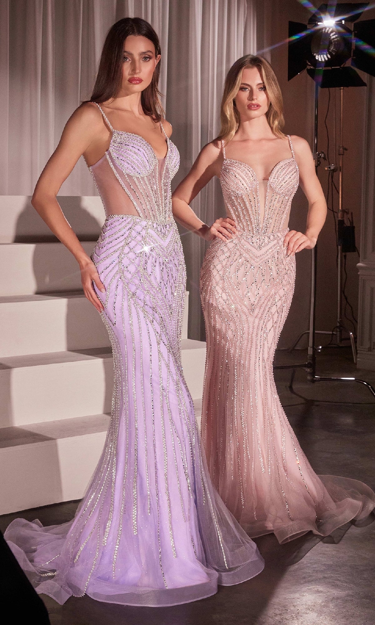 Two women pose indoors near white steps, wearing Ladivine CD759 long beaded mermaid prom dresses with sheer panels—one in lavender, the other in blush pink.