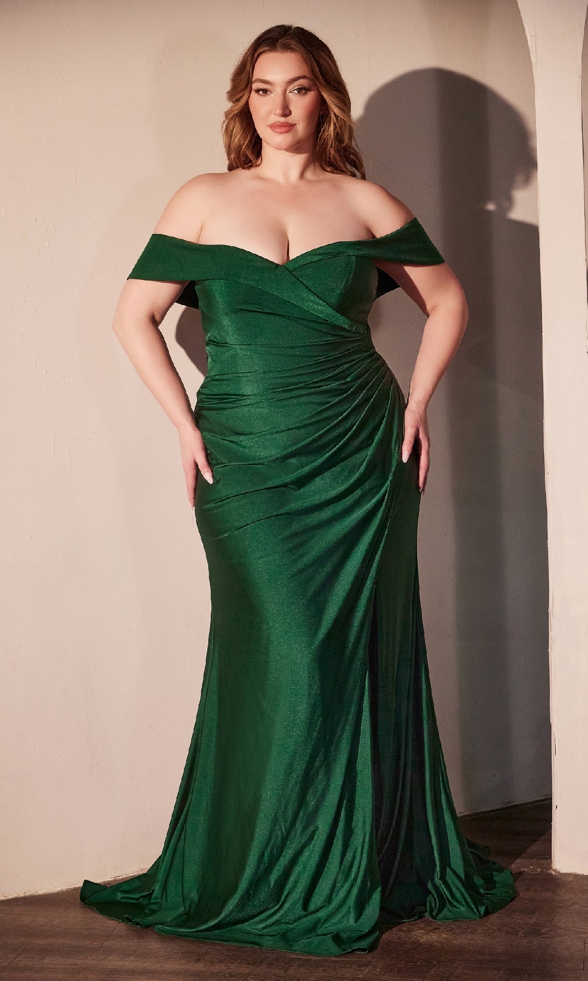 A person wearing the Off-Shoulder Plus-Size Prom Gown: Ladivine CD790C—a fitted green evening dress under $150—stands against a plain wall.