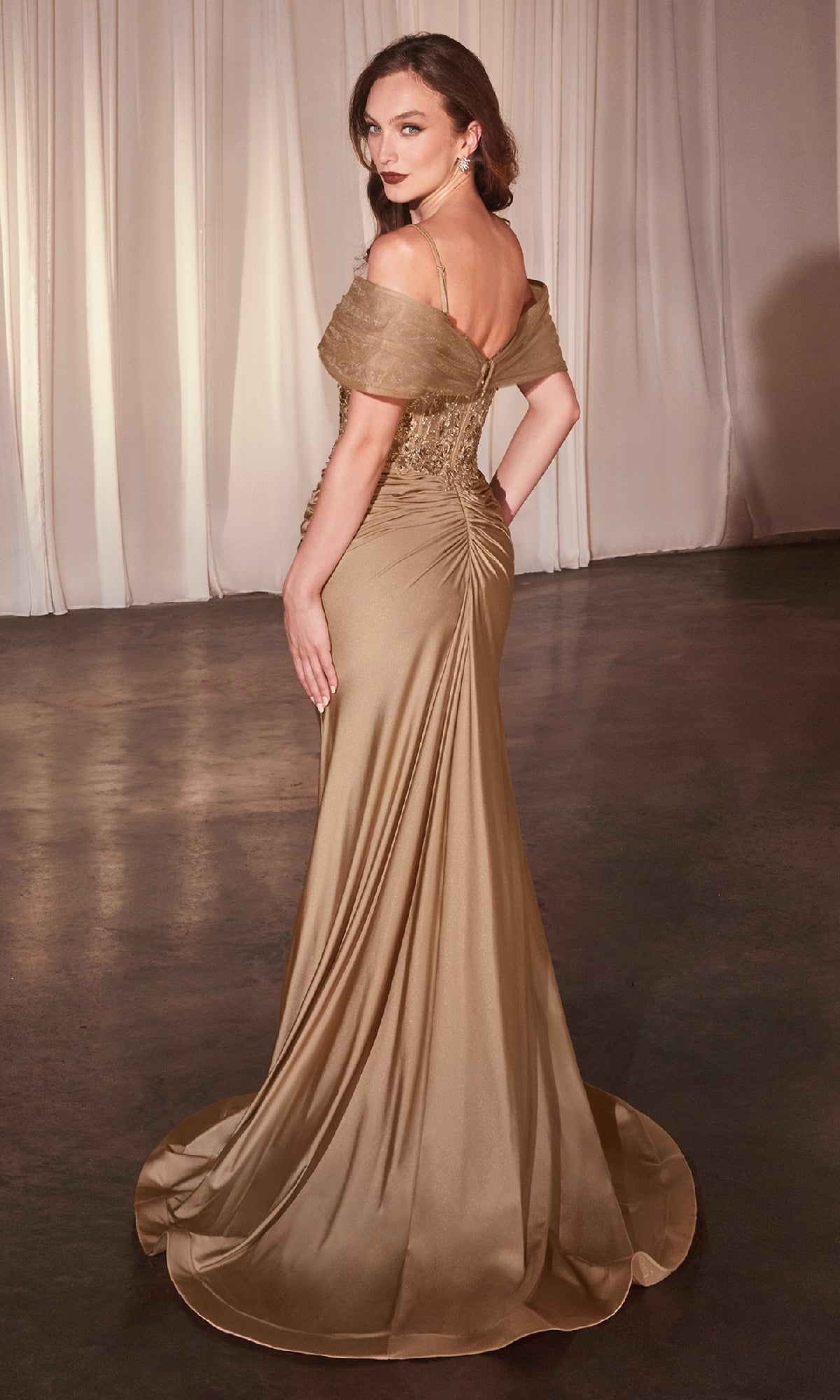 A woman wearing the Sheer Lace-Bodice Long Prom Dress (CLCD798) stands on a dark floor, facing away and glancing over her shoulder, with pale curtains in the background.