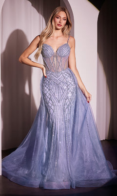 A woman poses in front of a white arched backdrop wearing the Beaded Overskirt Long Formal Prom Dress CD863, a sleeveless, fitted light blue gown with sheer panels and a flowing tulle train.