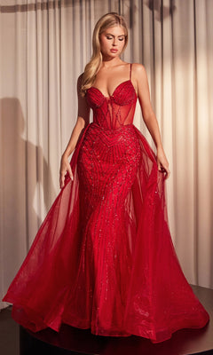 A woman stands on a black platform before white curtains, wearing the Beaded Overskirt Long Formal Prom Dress CD863 with a fitted bodice and flowing sheer red skirt.