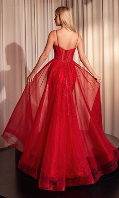 A woman stands facing away, holding the sides of her Beaded Overskirt Long Formal Prom Dress CD863—a red, floor-length formal gown with a sheer, sparkling overlay. White curtains are in the background.