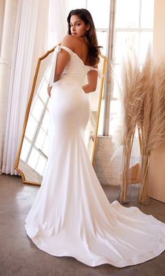 A woman in the Tie-Strap Long White Formal Dress: Ladivine CD944W stands before a tall mirror, surrounded by pampas grass decor and large windows in the background.