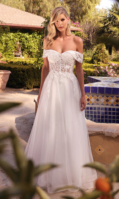 A woman in the Sheer-Bodice Long White Prom Ball Gown CD961W stands outdoors near a tiled fountain and lush garden.