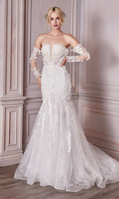 A woman poses against a paneled wall in the Long White Strapless Bridal Gown CD977W, featuring sheer long sleeves, embroidered floral designs, and delicate white lace.