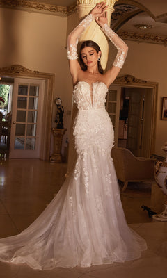 A woman models the Long White Strapless Bridal Gown CD977W, featuring embroidered floral designs and a fitted mermaid skirt, standing indoors with her arms raised above her head.