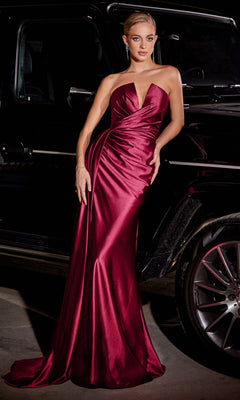 A woman wearing the Side-Drape Strapless Long Formal Dress CDS441 in deep red satin with a corset-style bodice stands beside a black luxury vehicle.
