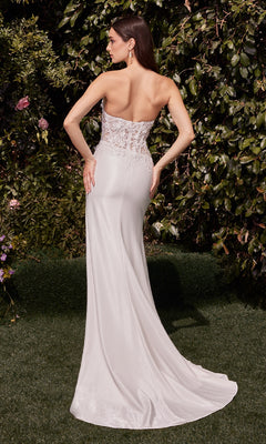 A woman stands outdoors amid lush greenery, facing away while wearing the Ladivine CDS465W strapless long corset prom dress featuring lace back detailing.