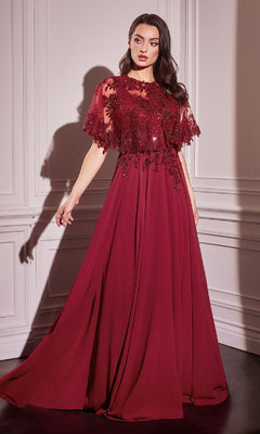A woman stands in a room wearing the Beaded-Cape Long Formal Dress (CLCDS503), a floor-length evening gown with glitter embroidery, lace and sequin detailing on the bodice, and sheer cape sleeves.