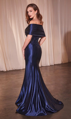 A woman stands on a concrete floor wearing the Off-Shoulder Wrap Long Prom Dress: Ladivine CDS507 in dark blue with a flowing skirt; cream curtains hang in the background.