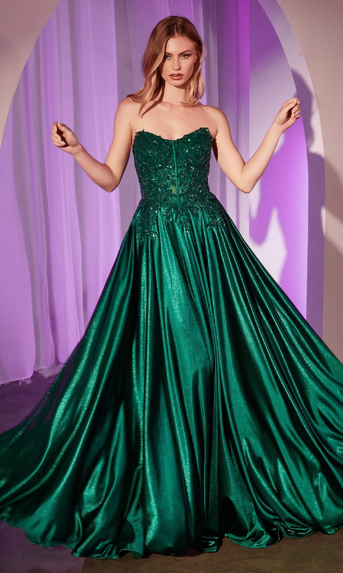 A woman stands in a formal setting wearing the Off-the-Shoulder Prom Ball Gown: Ladivine CDS525, a dark green ball gown featuring an off-the-shoulder neckline, fitted bodice, and full flowing skirt.