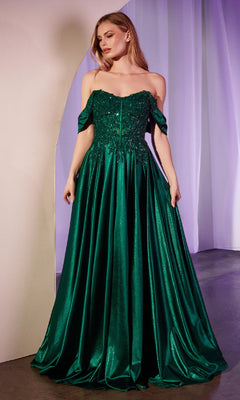 A woman stands indoors wearing the Off-the-Shoulder Prom Ball Gown: Ladivine CDS525 in emerald green, featuring a fitted embellished bodice and flowing satin skirt.