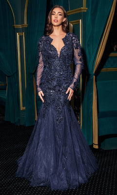 Woman in a dark blue evening gown with long sleeves against a decorative green and gold background
