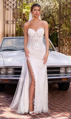 A woman in the Ladivine CDS550W Long Wedding Dress in off white, featuring a strapless design with delicate floral lace and a thigh-high slit, stands in front of a vintage white car and metal gates.