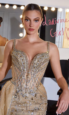 A woman in a gold beaded Ladivine CDS570 long prom dress sits at a lit vanity with "Ladivine Girls" written in pink on the mirror.