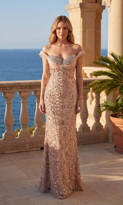 A woman in the champagne Long Prom Dress: Chicas CF2510 with a beaded corset bodice stands on a stone terrace, with the sea and palm plant in the background.