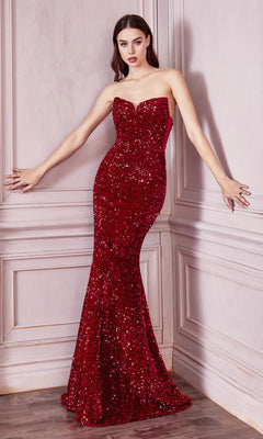 A woman stands against light-paneled walls in the Sheer-Sides Strapless Long Sequin Prom Dress CH151, its striking red sequins shimmering on the elegant, strapless formal gown.