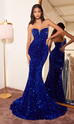A woman poses in front of a mirror wearing the Sheer-Sides Strapless Long Sequin Prom Dress CH151, a fitted royal blue gown that shimmers beautifully in the dressing room.