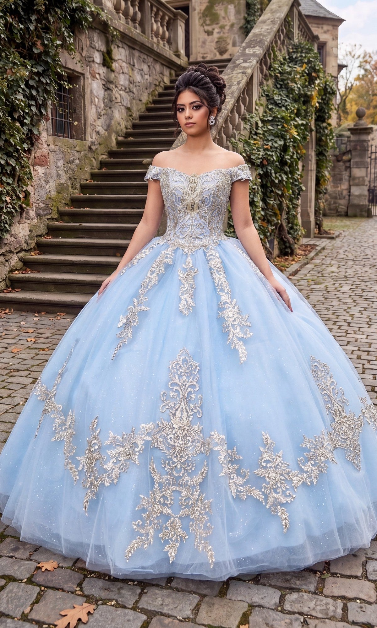 A woman wearing the Quinceanera Dress CHF3006 By Chicas in baby blue and gold stands on a cobblestone path beside stone steps and ivy-covered walls.