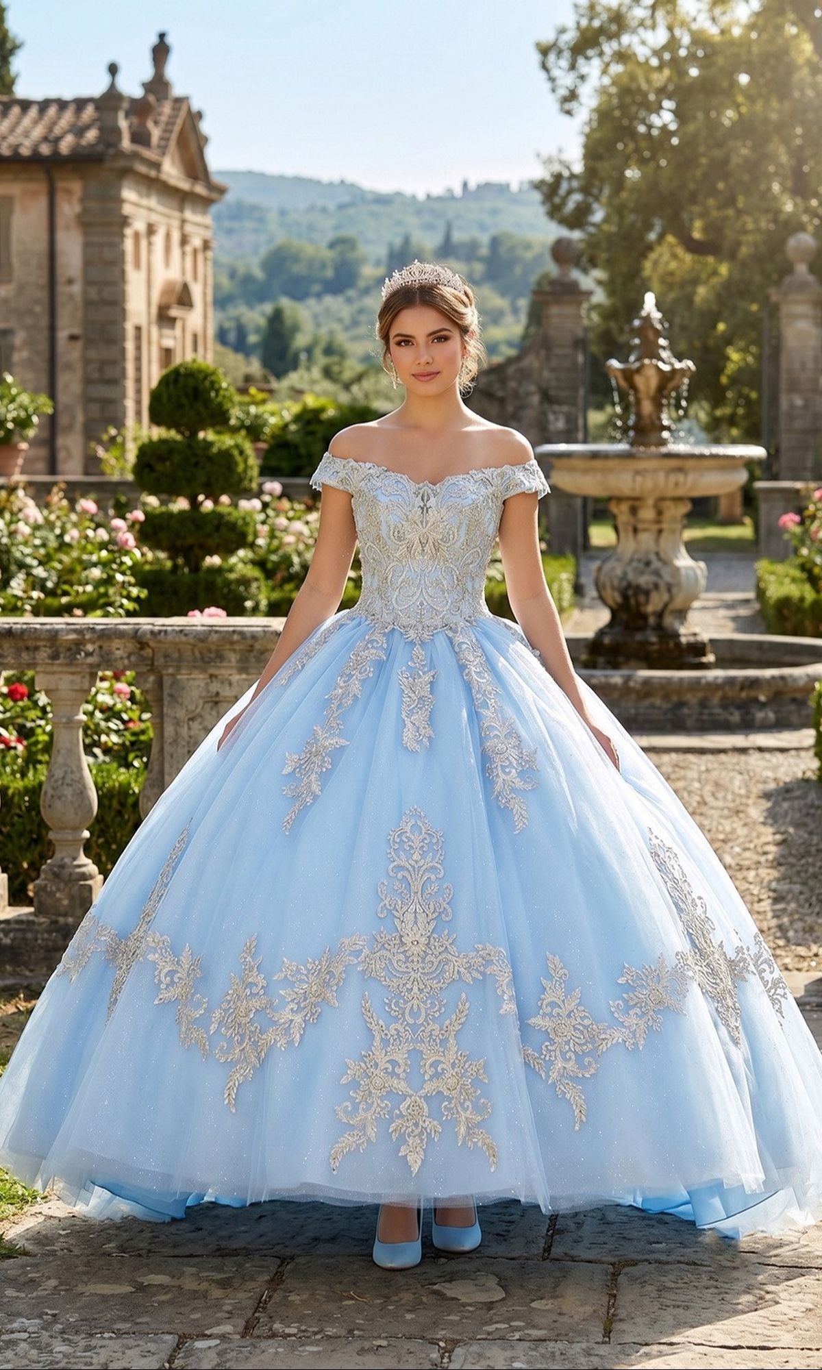 A young woman in the Quinceanera Dress CHF3008 by Chicas, featuring an off-the-shoulder baby blue and gold ball gown, stands in a garden with stone railings, a fountain, and lush greenery in the background.