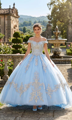 A young woman in the Quinceanera Dress CHF3008 by Chicas, featuring an off-the-shoulder baby blue and gold ball gown, stands in a garden with stone railings, a fountain, and lush greenery in the background.