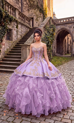 A woman in the Quinceanera Dress CHF3009 by Chicas, featuring a lavender and silver color palette, stands on a cobblestone path near stone stairs and ivy-covered walls.
