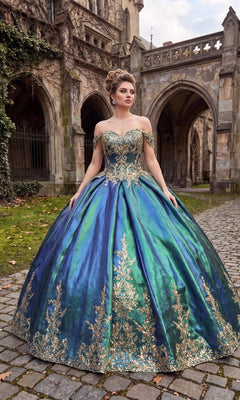 A woman stands on cobblestone in front of a stone building, wearing the Quinceanera Dress CHF3015 by Chicas in hunter green and gold, featuring an off-shoulder design and shimmering gold embellishments adorning its flowing ballgown skirt.