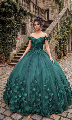 A woman stands on a cobblestone path in front of stone stairs and ivy-covered walls, wearing the Quinceanera Dress CHF3030 By Chicas—a green, off-the-shoulder gown adorned with delicate 3D floral accents.