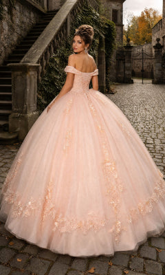 A woman wearing the Quinceanera Dress CHF3041 By Chicas, an off-the-shoulder pink ballgown skirt, stands on a cobblestone path near stone stairs and glances over her shoulder in a charming, historic outdoor setting.