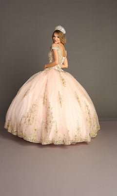 Wearing the Quinceanera Dress CHF3051 By Chicas, a woman stands in front of a plain gray background, her back to the camera as she looks over her shoulder. The light pink off-the-shoulder gown features intricate gold embroidery and is complemented by a jeweled crown.