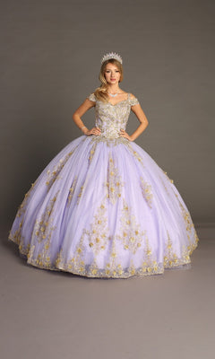 A woman stands against a plain gray background wearing the Quinceanera Dress CHF3051 By Chicas in lilac and gold, featuring an off-the-shoulder design with gold embroidery and a tiara.