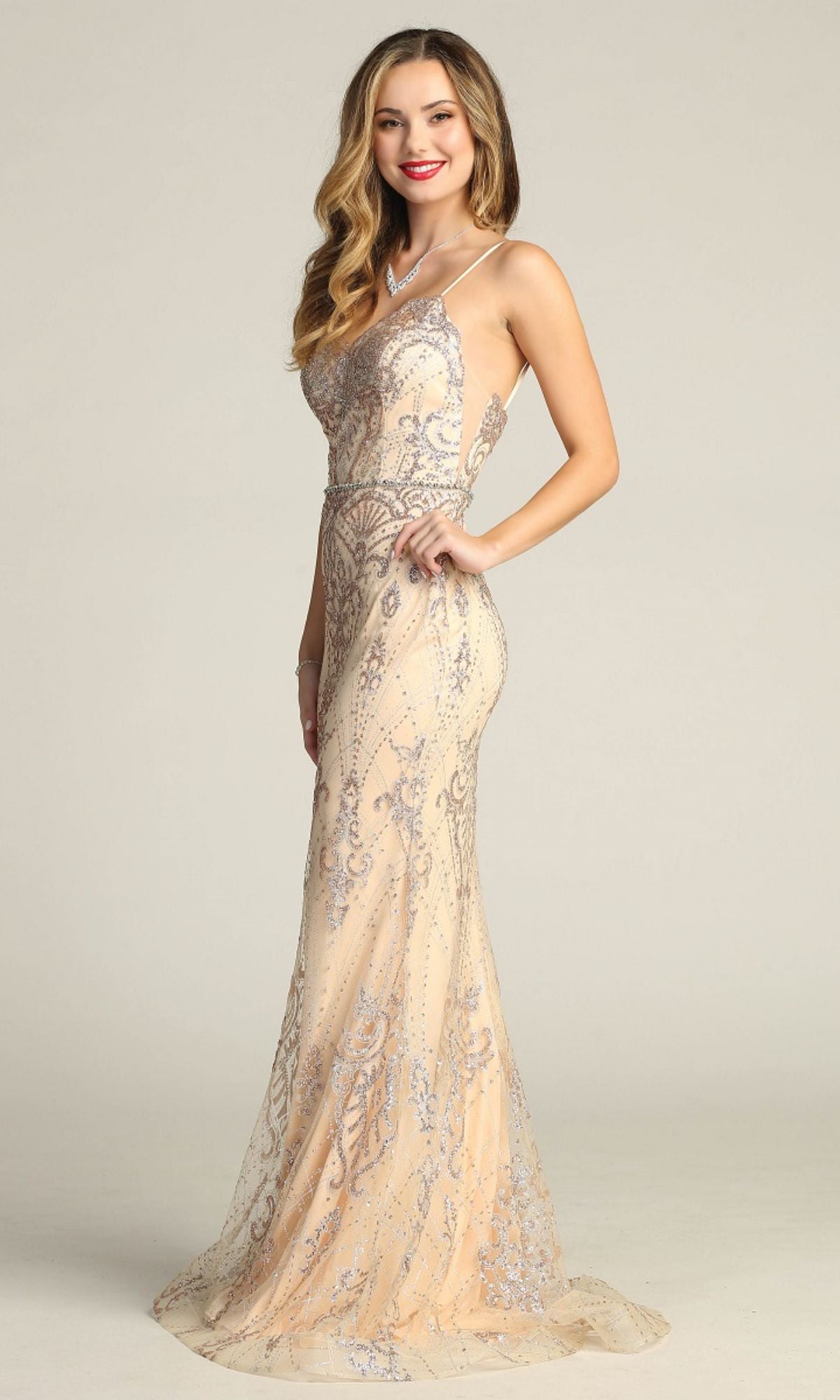 A woman poses against a plain light background wearing the Lace-Up Long Glitter Prom Dress: Chicas CHF3053, a fitted, floor-length sequin gown with intricate silver embellishments.