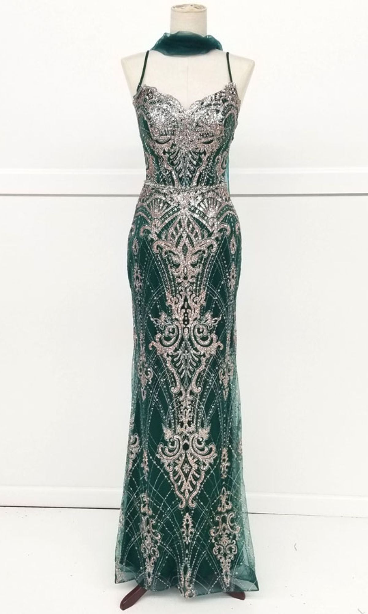 A mannequin displays the Chicas CHF3053 Lace-Up Long Glitter Prom Dress, a floor-length, sleeveless gown with thin straps and intricate silver patterns.