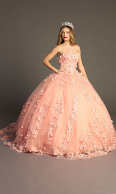 A woman wearing a silver tiara and a strapless Quinceanera Dress CHF3055 By Chicas in coral stands against a plain backdrop. Her exquisite ball gown features delicate 3D floral appliques, adding stunning detail to the elegant silhouette.