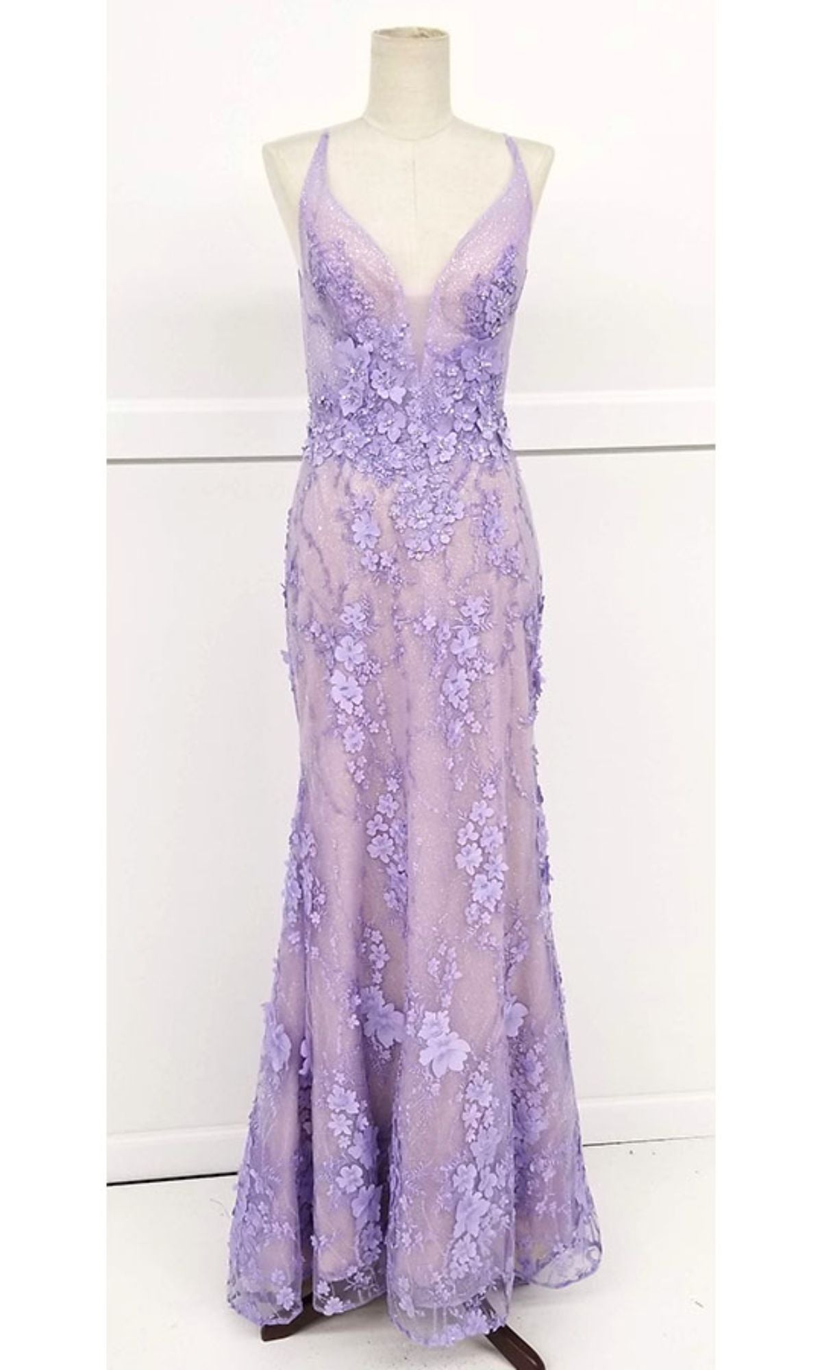 A mannequin showcases the Floral-Lace Long Prom Dress: Chicas CHF3058, a floor-length lavender gown with an open back, sleeveless design, deep V-neckline, and elegant floral lace appliqué.