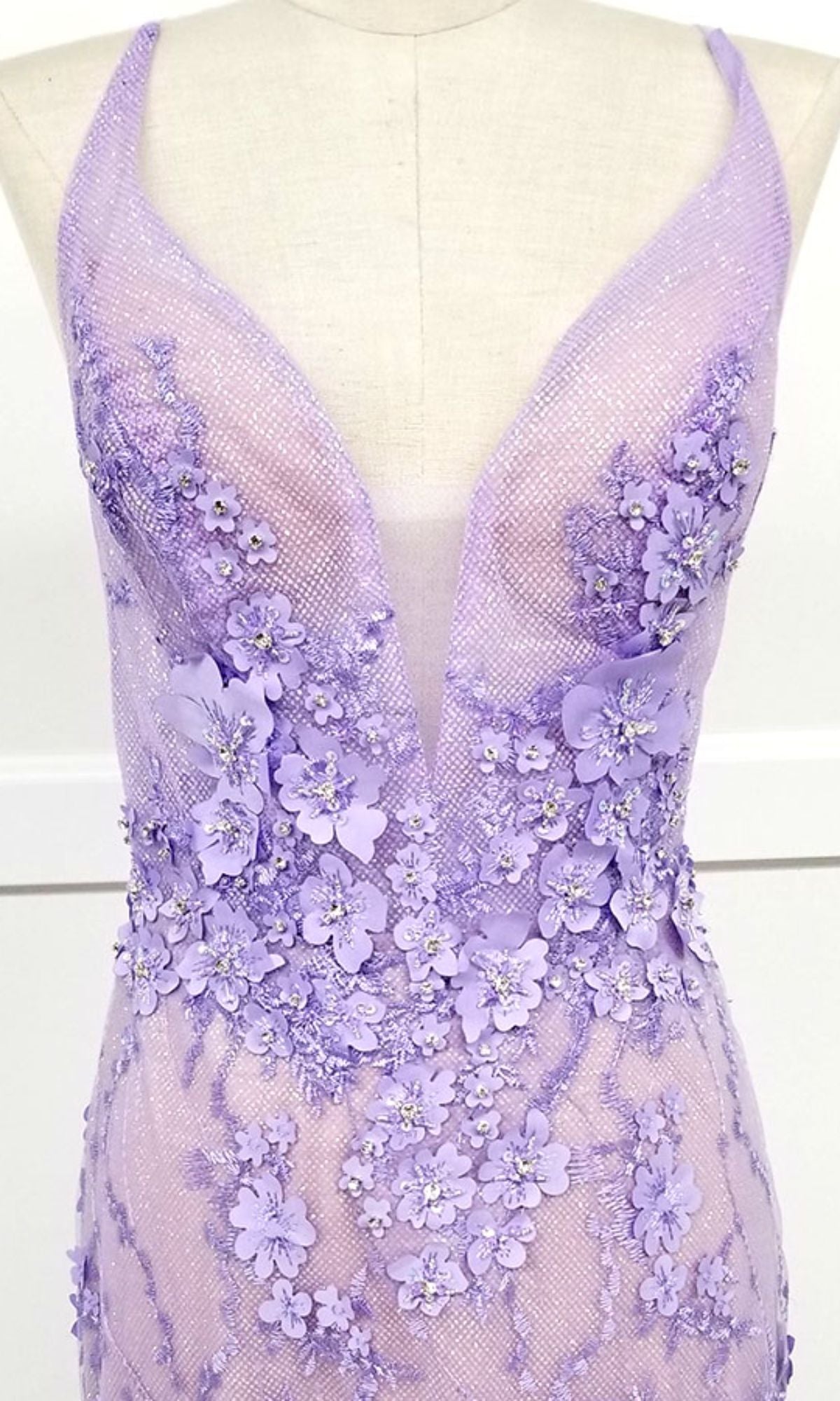 The Chicas CHF3058 Floral-Lace Long Prom Dress features lavender sheer floral lace with a deep V neckline, 3D floral appliqués, and beading, displayed on a mannequin.