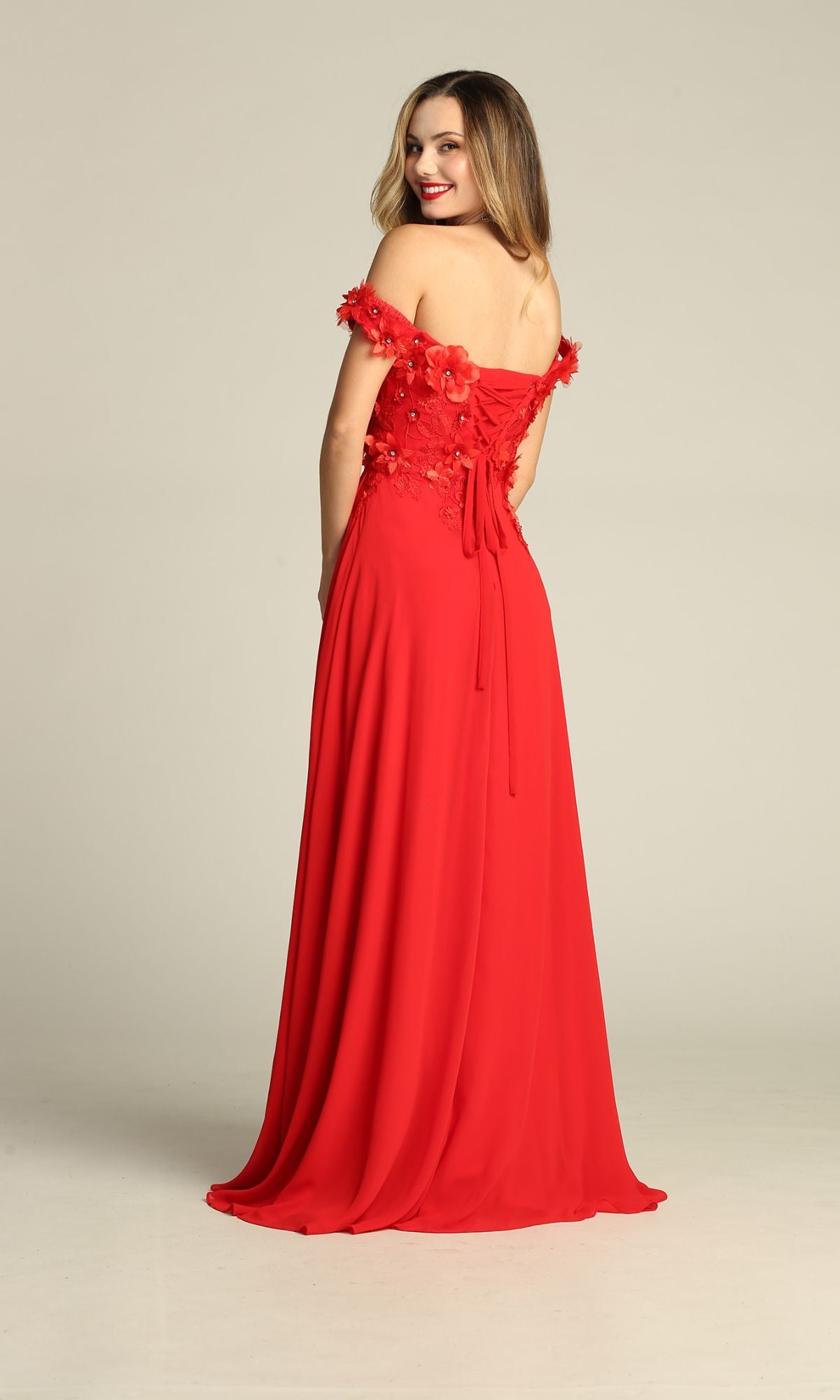 A woman smiles over her shoulder while wearing the Off-Shoulder Long A-Line Prom Dress: Chicas CHF3059, a floor-length red gown with floral embellishments.