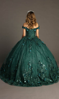 A person with long wavy hair wears the Quinceanera Dress CHF3069 By Chicas, a green, off-the-shoulder ballgown adorned with 3D floral appliques, along with a tiara, standing against a plain backdrop.