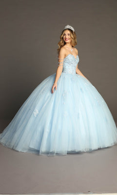 A woman stands and smiles against a plain gray background, wearing the Quinceanera Dress CHF3071 By Chicas—a light blue glitter-tulle ballgown with a beaded bodice and a silver tiara.