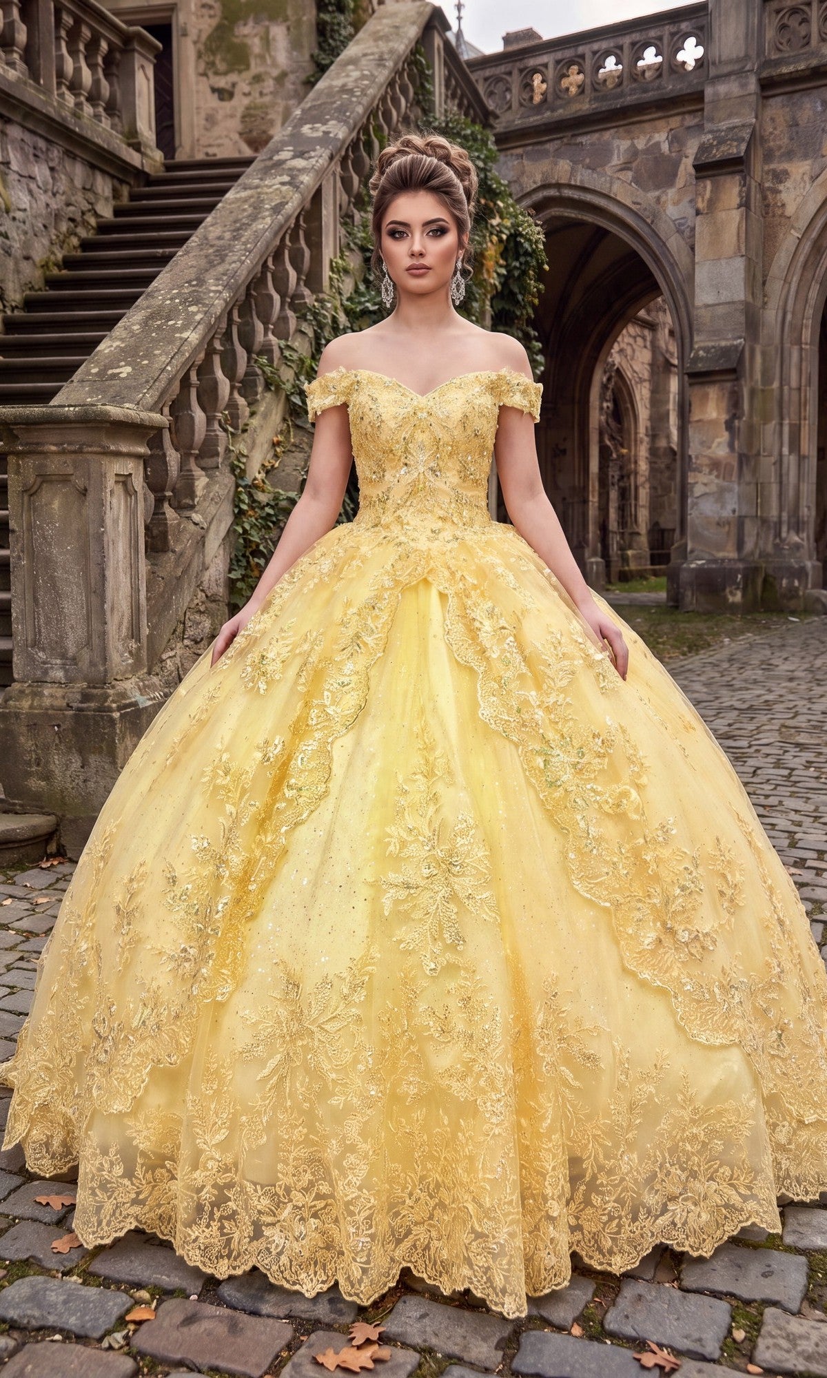 A woman wearing the Quinceanera Dress CHF3072 By Chicas in yellow, featuring intricate metallic embroidery and an ornate off-the-shoulder design, stands on a cobblestone path before a historic stone staircase and building, her dramatic ballgown skirt elegantly fanned around her.