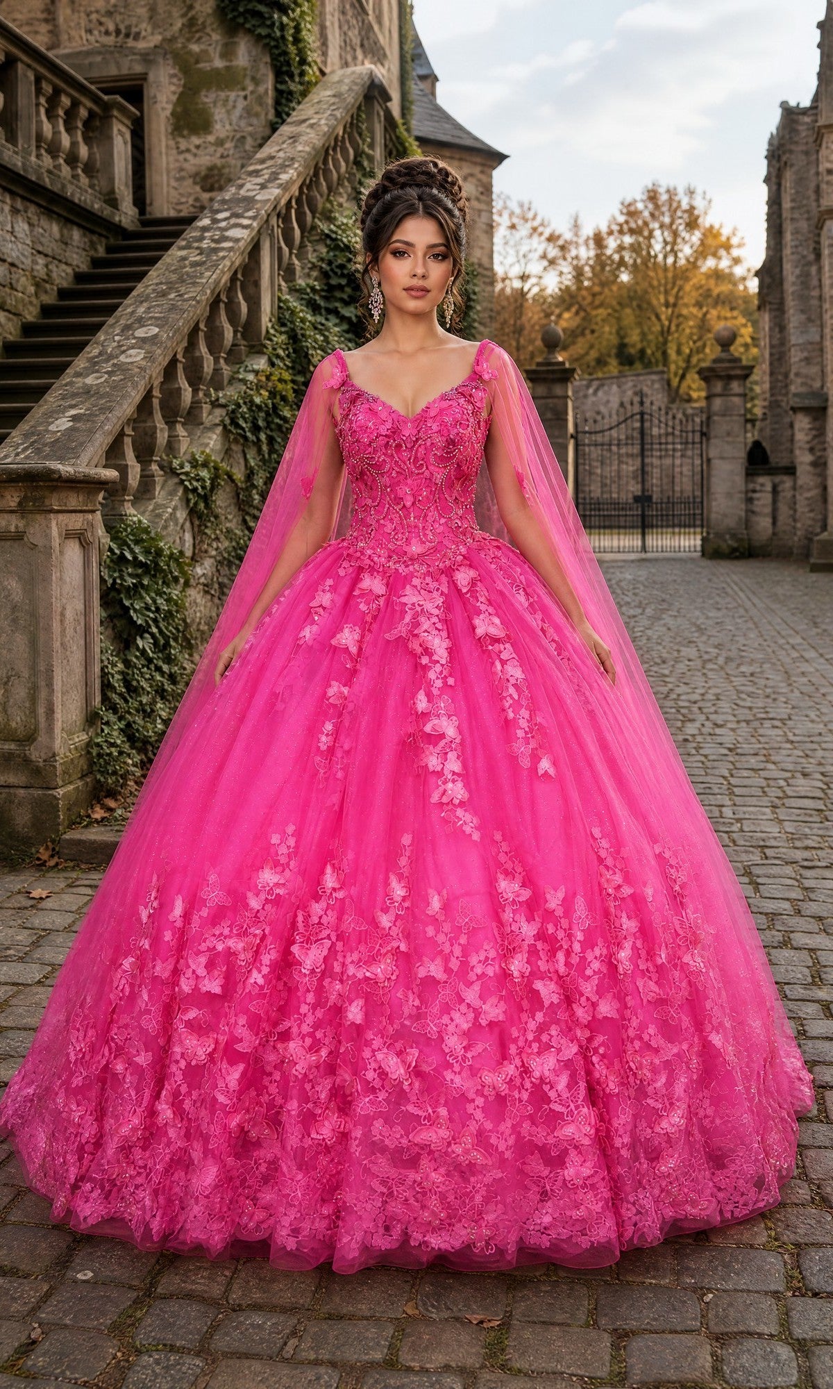 A woman wearing the Quinceanera Dress CHF3077 by Chicas, featuring bright pink fabric with delicate floral lace details and sparkling glitter tulle in a ballgown silhouette, stands on a cobblestone path near stone steps and old buildings.