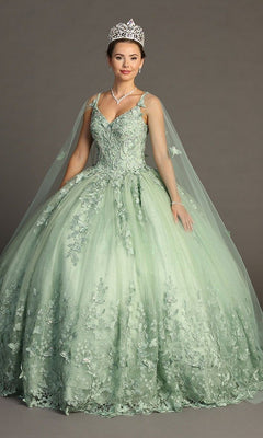 A woman wearing the Quinceanera Dress CHF3077 by Chicas—a light green glitter tulle ballgown adorned with floral lace details and delicate butterfly appliques—paired with a tiara and necklace, stands in front of a plain gray background.