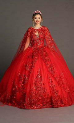 A woman is wearing the Quinceanera Dress CHF3080 By Chicas, an ornate, bright red gown featuring a cape and exquisite 3D floral appliques, as she stands against a plain gray background.