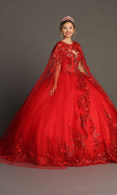 A woman wearing the Quinceanera Dress CHF3080 By Chicas—a bright red glitter tulle ballgown with intricate 3D floral appliques, a matching cape, and a tiara—stands against a plain gray background.