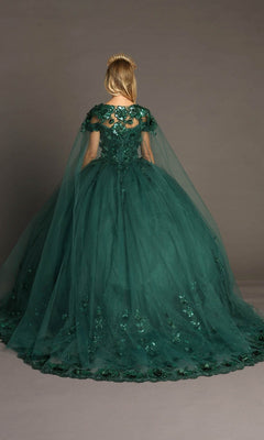 A person is shown from behind, standing against a plain gray background, wearing the Quinceanera Dress CHF3082 By Chicas—a floor-length, dark green gown featuring a cape and delicate 3D floral appliqués.